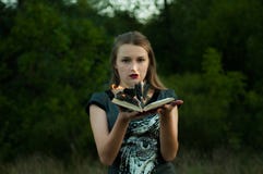 Классическая версия стиля ведьм Девушка в ее оружии горящая книга огня стоковая фотография rf Классическая версия стиля ведьм Девушка в ее оружии горящая книга огня стоковая фотография rf