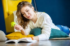 Книга чтения женщины дома и кладущ на пол рядом с желтым креслом стоковое фото Книга чтения женщины дома и кладущ на пол рядом с желтым креслом стоковое фото