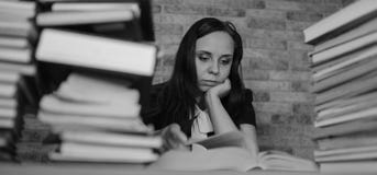 Книга чтения студента женщины буря на библиотеке с много книгами в университете Привоженная в уныние студентом книга чтения для стоковое изображение rf Книга чтения студента женщины буря на библиотеке с много книгами в университете Привоженная в уныние студентом книга чтения для стоковое изображение rf