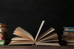Книги и раскрытая книга на коричневом деревянном столе и на черной предпосылке записывает старую Образование школа изучение стоковая фотография Книги и раскрытая книга на коричневом деревянном столе и на черной предпосылке записывает старую Образование школа изучение стоковая фотография