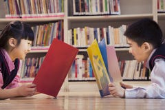 Книги чтения ребеят школьного возраста в библиотеке стоковое фото Книги чтения ребеят школьного возраста в библиотеке стоковое фото