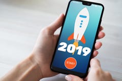 кнопка начала Ракеты 2019 год на экране мобильного телефона владение домашнего ключа принципиальной схемы дела золотистое достига стоковая фотография rf кнопка начала Ракеты 2019 год на экране мобильного телефона владение домашнего ключа принципиальной схемы дела золотистое достига стоковая фотография rf