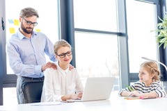 Коммерсантка и бизнесмен при eyeglasses работая при дочь компьтер-книжки рисуя близко в офисе Стоковые Фотографии RF Коммерсантка и бизнесмен при eyeglasses работая при дочь компьтер-книжки рисуя близко в офисе Стоковые Фотографии RF