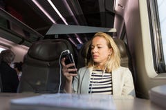 Коммерсантка связывая на мобильном телефоне пока путешествующ поездом Стоковое Изображение Коммерсантка связывая на мобильном телефоне пока путешествующ поездом Стоковое Изображение