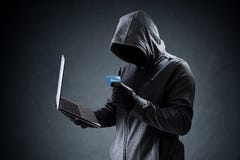 Компьютерный хакер с кредитной карточкой крадя данные от компьтер-книжки Компьютерный хакер с кредитной карточкой крадя данные от компьтер-книжки