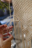 Конец вверх по рукам сплетя гобелен macrame с бежевым потоком стоковые фото Конец вверх по рукам сплетя гобелен macrame с бежевым потоком стоковые фото