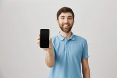 Концепция рекламы Симпатичный продавец показывая smartphone к камере пока усмехающся и был дружелюбный стоковая фотография Концепция рекламы Симпатичный продавец показывая smartphone к камере пока усмехающся и был дружелюбный стоковая фотография