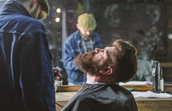 Концепция холить Битник при борода предусматриванная с утеской накидки профессиональным парикмахером в стильной парикмахерскае ba стоковое изображение Концепция холить Битник при борода предусматриванная с утеской накидки профессиональным парикмахером в стильной парикмахерскае ba стоковое изображение