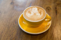 Кофе искусства latte Rosetta и желтая чашка на деревянной таблице стоковое изображение Кофе искусства latte Rosetta и желтая чашка на деревянной таблице стоковое изображение