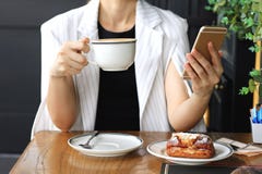 Кофе молодой коммерсантки выпивая и использование умного телефона в кафе, бизнес-леди работая на ее перерыве на чашку кофе в баре стоковые изображения rf Кофе молодой коммерсантки выпивая и использование умного телефона в кафе, бизнес-леди работая на ее перерыве на чашку кофе в баре стоковые изображения rf