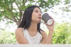 Кофе молодой женщины выпивая от устранимой чашки Азиатская девушка держа кофейную чашку с зеленой природой стоковое фото rf Кофе молодой женщины выпивая от устранимой чашки Азиатская девушка держа кофейную чашку с зеленой природой стоковое фото rf