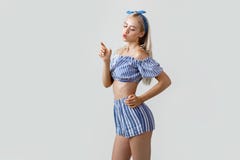 Красивая белокурая девушка в обмундировании лета, представляя на камере держа что-то как бутылка в ее руке и напитках оно стоковая фотография Красивая белокурая девушка в обмундировании лета, представляя на камере держа что-то как бутылка в ее руке и напитках оно стоковая фотография