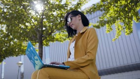 Красивая бизнес-леди в солнечных очках одетых в костюме используя ноутбук во время перерыва outdoors, сидеть молодой женщины сток-видео Красивая бизнес-леди в солнечных очках одетых в костюме используя ноутбук во время перерыва outdoors, сидеть молодой женщины сток-видео