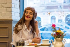 Красивая девушка в берете сидит на таблице в кафе с чашкой чаю, macaroons стоковые изображения rf Красивая девушка в берете сидит на таблице в кафе с чашкой чаю, macaroons стоковые изображения rf