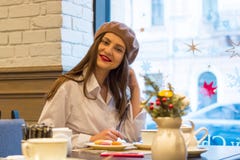 Красивая девушка в берете сидит на таблице в кафе с чашкой чаю, macaroons стоковые фото Красивая девушка в берете сидит на таблице в кафе с чашкой чаю, macaroons стоковые фото
