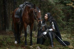 Красивая девушка ратника с chainmail шпаги нося и панцырь с лошадью в загадочном лесе Стоковые Изображения Красивая девушка ратника с chainmail шпаги нося и панцырь с лошадью в загадочном лесе Стоковые Изображения