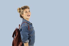 Красивая девушка студента в куртке джинсовой ткани с рюкзаком на ее плечах в студии на голубой предпосылке Концепция стоковое изображение rf Красивая девушка студента в куртке джинсовой ткани с рюкзаком на ее плечах в студии на голубой предпосылке Концепция стоковое изображение rf