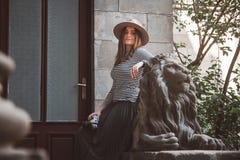 Красивая женщина в striped рубашке и шляпе Держит камеру около статуи льва на фоне старой стоковые фото Красивая женщина в striped рубашке и шляпе Держит камеру около статуи льва на фоне старой стоковые фото