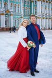 Красивая женщина в красном платье и человеке представляя положение в зиме, свадьбе в Санкт-Петербурге стоковое изображение rf Красивая женщина в красном платье и человеке представляя положение в зиме, свадьбе в Санкт-Петербурге стоковое изображение rf