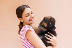 Красивая женщина держа и смотря в черное ` s щенка наблюдает стоковое фото rf Красивая женщина держа и смотря в черное ` s щенка наблюдает стоковое фото rf