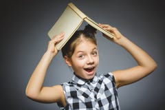 Красивая маленькая девочка при усмехаться книги изолированный на серой предпосылке стоковые изображения rf Красивая маленькая девочка при усмехаться книги изолированный на серой предпосылке стоковые изображения rf