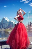 Красивая маленькая девочка на крыше здания в красном сочном платье стоковая фотография Красивая маленькая девочка на крыше здания в красном сочном платье стоковая фотография