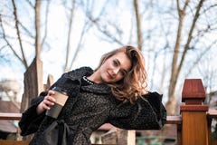 Красивая маленькая девочка представляя с кофе на открытом воздухе стоковая фотография rf Красивая маленькая девочка представляя с кофе на открытом воздухе стоковая фотография rf