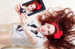 Красивая молодая привлекательная девушка pinup женщины лежа и принимая selfy или изображение selfie на цифровом планшете стоковое изображение rf Красивая молодая привлекательная девушка pinup женщины лежа и принимая selfy или изображение selfie на цифровом планшете стоковое изображение rf