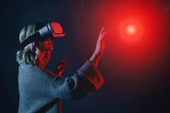 Красивая молодая белокурая женщина нося стекла VR касаясь мнимому объекту в воздухе во время опыта виртуальной реальности стоковое фото rf Красивая молодая белокурая женщина нося стекла VR касаясь мнимому объекту в воздухе во время опыта виртуальной реальности стоковое фото rf