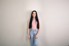 Красивая молодая женщина брюнета с длинными волосами готовит серую предпосылку смотря прямо к камере носить стоковое изображение Красивая молодая женщина брюнета с длинными волосами готовит серую предпосылку смотря прямо к камере носить стоковое изображение