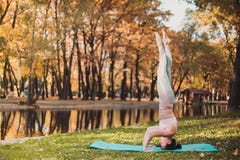 Красивая молодая женщина практикует asana йоги на деревянном столе в парке осени стоковые фотографии rf Красивая молодая женщина практикует asana йоги на деревянном столе в парке осени стоковые фотографии rf