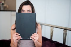 Красивая молодая женщина смотря над бумагами в ее руках которые прячут ее сторону стоковые фотографии rf Красивая молодая женщина смотря над бумагами в ее руках которые прячут ее сторону стоковые фотографии rf