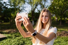 Красивая молодая женщина со светлыми волосами используя мобильный телефон на открытом воздухе Стильная девушка делая selfie стоковое фото rf Красивая молодая женщина со светлыми волосами используя мобильный телефон на открытом воздухе Стильная девушка делая selfie стоковое фото rf