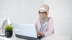 Красивая молодая мусульманская женщина работает на ноутбуке на ее рабочем месте сток-видео Красивая молодая мусульманская женщина работает на ноутбуке на ее рабочем месте сток-видео