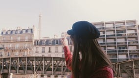 Красивая молодая счастливая туристская женщина усмехаясь, указывающ на солнечный взгляд Эйфелевой башни на замедленном движении б сток-видео Красивая молодая счастливая туристская женщина усмехаясь, указывающ на солнечный взгляд Эйфелевой башни на замедленном движении б сток-видео