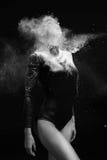 Красивая тонкая девушка нося гимнастический bodysuit покрытый с облаками белых представлений летая порошка на темную предпосылку стоковое изображение rf Красивая тонкая девушка нося гимнастический bodysuit покрытый с облаками белых представлений летая порошка на темную предпосылку стоковое изображение rf