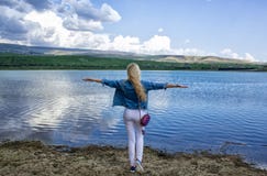 Красивая худенькая молодая женщина стоит с ее задней частью на береге стоковое изображение rf Красивая худенькая молодая женщина стоит с ее задней частью на береге стоковое изображение rf