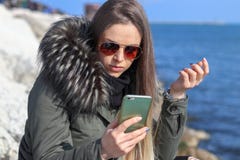 красивейшая девушка Счастливая женщина смотря к телефону на пляже с морем на заднем плане стоковая фотография красивейшая девушка Счастливая женщина смотря к телефону на пляже с морем на заднем плане стоковая фотография
