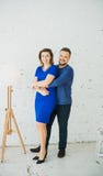 Красивые стильные молодые пары дома обнимая и смеясь на камере Вертикальная рамка голубое maike платья стоковое фото rf Красивые стильные молодые пары дома обнимая и смеясь на камере Вертикальная рамка голубое maike платья стоковое фото rf