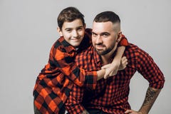 Красивый бородатый человек и мальчик на его назад смотрят камеру стоковая фотография rf Красивый бородатый человек и мальчик на его назад смотрят камеру стоковая фотография rf