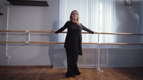 Красивый женский артист балета в silk черном костюме стоя близко barre балета в классе и делая exersice с ей видеоматериал Красивый женский артист балета в silk черном костюме стоя близко barre балета в классе и делая exersice с ей видеоматериал