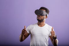 Красивый молодой африканский человек в положении шлемофона VR против пурпурной предпосылки стоковое фото Красивый молодой африканский человек в положении шлемофона VR против пурпурной предпосылки стоковое фото