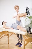 Красивый молодой человек во время встречи физиотерапии с профессиональным доктором стоковое изображение rf Красивый молодой человек во время встречи физиотерапии с профессиональным доктором стоковое изображение rf