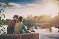 Красивый отец и сын сидя в шлюпке на озере пока наслаждающся удить совместно стоковое фото Красивый отец и сын сидя в шлюпке на озере пока наслаждающся удить совместно стоковое фото