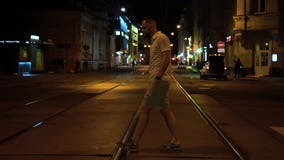 Красивый подходящий бородатый человек в striped поло и зеленые шорты пересекают дорогу вечером на crosswalk сток-видео Красивый подходящий бородатый человек в striped поло и зеленые шорты пересекают дорогу вечером на crosswalk сток-видео