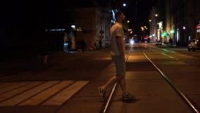 Красивый подходящий бородатый человек в striped поло и зеленые шорты пересекают дорогу вечером на crosswalk сток-видео Красивый подходящий бородатый человек в striped поло и зеленые шорты пересекают дорогу вечером на crosswalk сток-видео
