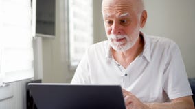 Красивый пожилой старший человек работая на портативном компьютере дома Работа Remote независимая на выходе на пенсию стоковые фотографии rf Красивый пожилой старший человек работая на портативном компьютере дома Работа Remote независимая на выходе на пенсию стоковые фотографии rf