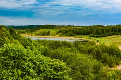 Красивый сельский ландшафт лета с лесом, рекой, голубым небом и белыми облаками стоковые изображения rf Красивый сельский ландшафт лета с лесом, рекой, голубым небом и белыми облаками стоковые изображения rf