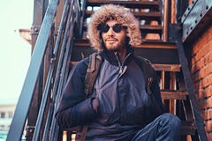 Красивый стильный молодой человек сидя на лестницах снаружи стоковые изображения Красивый стильный молодой человек сидя на лестницах снаружи стоковые изображения