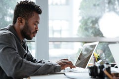 Красивый думая серьезный молодой человек сидя в офисе coworking Стоковое Изображение RF Красивый думая серьезный молодой человек сидя в офисе coworking Стоковое Изображение RF